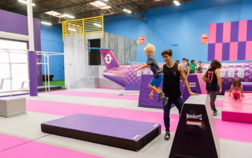 a man and a woman running on a mat in a gym