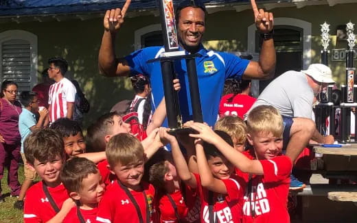 a person holding a trophy surrounded by kids