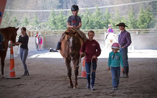 a person riding a horse with a child on a leash