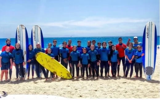 a group of people posing with surfboards on a beach