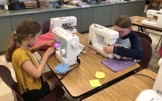 a couple of children working on a sewing machine