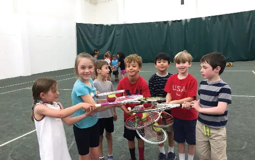 a group of kids holding tennis rackets