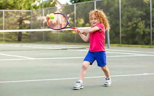 a girl hitting a ball with a tennis racket