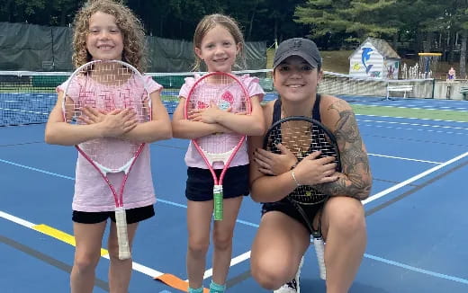 a group of girls posing for a picture on a tennis court