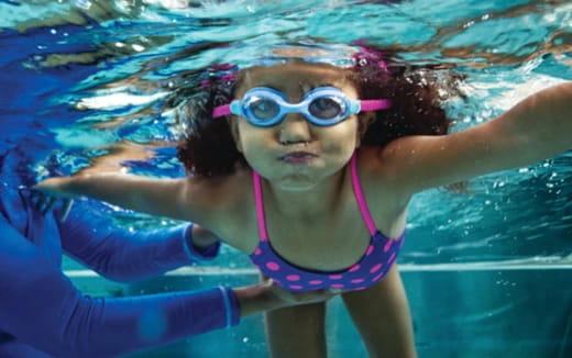 a girl wearing goggles and swimming