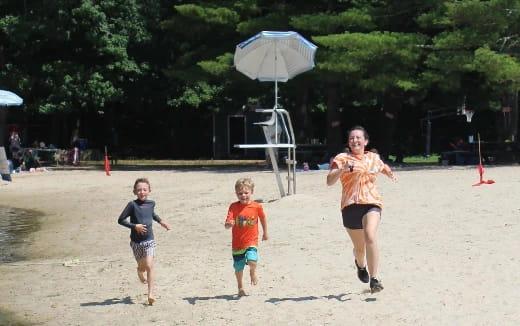 a person and two children running on a beach