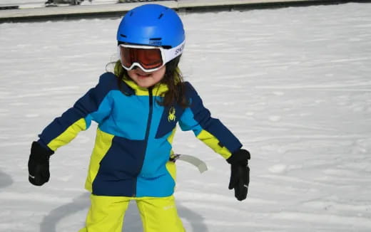 a girl wearing a helmet and goggles on ice