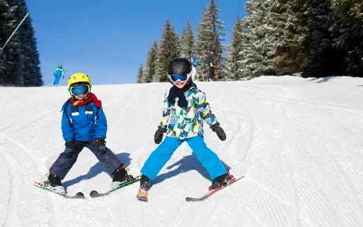a couple of kids skiing down a slope
