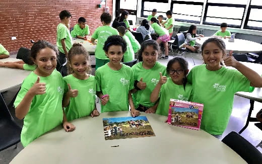 a group of children in green t-shirts sitting at a table