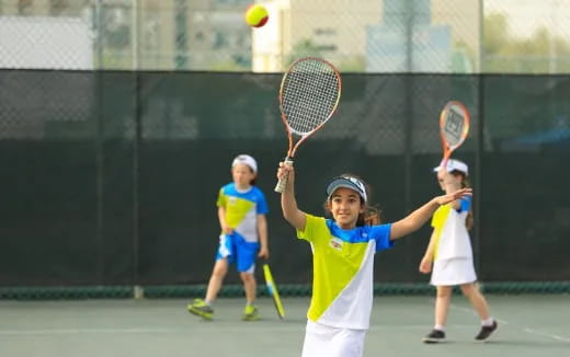 a group of kids playing tennis