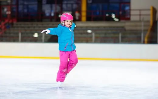 a girl wearing a helmet and ice skates on ice