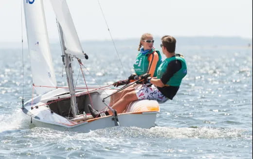 a couple of people on a sailboat in the water