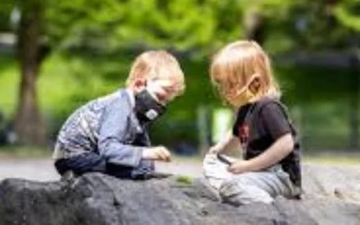 a couple of children sitting on a rock