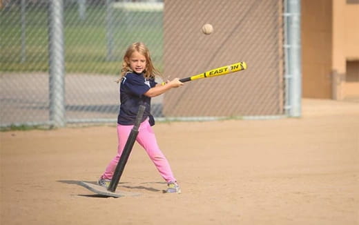 a girl hitting a ball with a bat