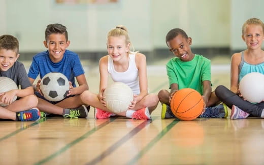 a group of kids sitting on the floor with balls