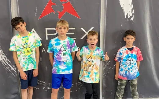 a group of boys standing in front of a wall with a flag