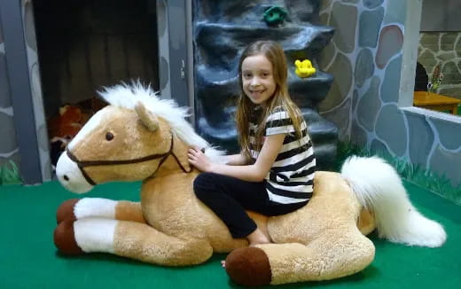 a girl sitting on a stuffed animal