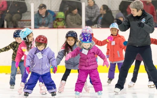 a group of kids wearing helmets and ice skates