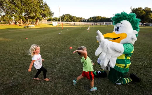 a couple children playing with a mascot