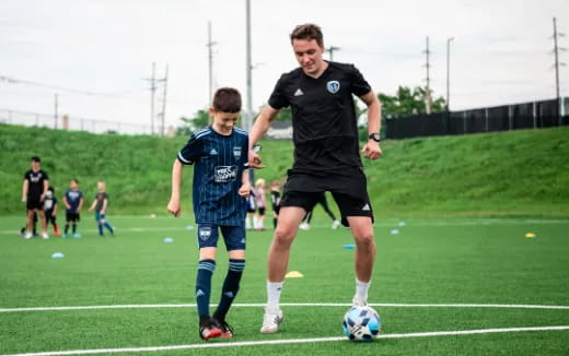 a person in a black shirt playing football with a person in a blue shirt