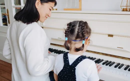 a woman and a child playing piano