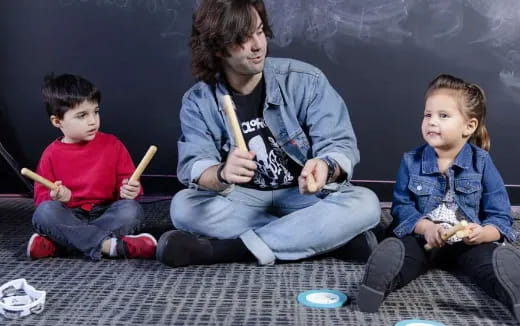 a person and two children sitting on the floor holding sticks