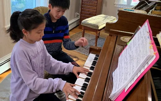 a boy and girl playing piano