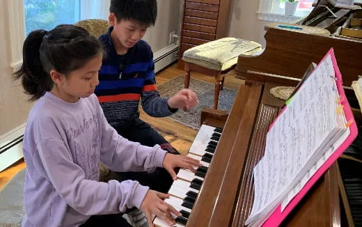 a boy and girl playing piano