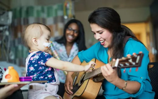 a person playing a guitar with a young girl