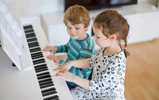 a couple of children playing a piano