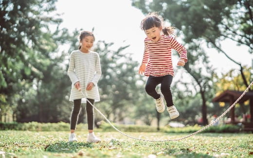 a couple of children running on a grass field