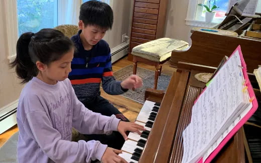 a boy and girl playing piano