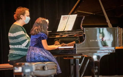a couple of women playing piano