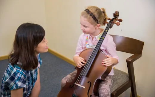 a girl playing a cello next to a girl