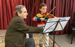 a man playing a musical instrument with a boy watching