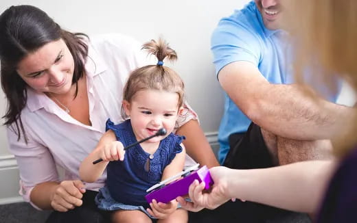 a group of people helping a child with a toothbrush