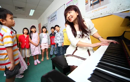 a person playing a piano in a classroom with children