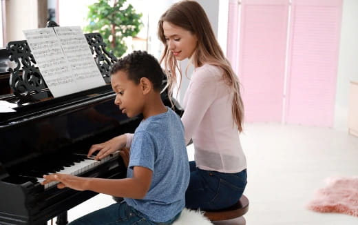 a woman and a boy playing piano