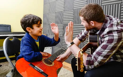 a man playing a guitar to a young boy