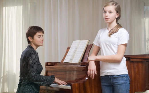 a woman playing a piano next to a woman