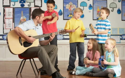 a person playing a guitar in front of a group of children
