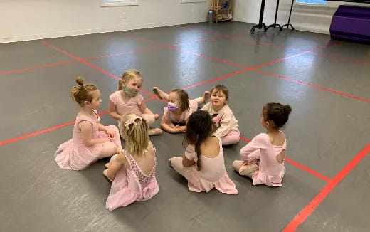 a group of girls in pink dresses sitting on the floor