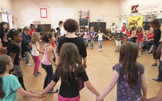 a group of children dancing in a room with other people