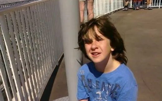 a child leaning against a fence