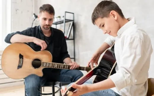 a person playing a guitar next to another man