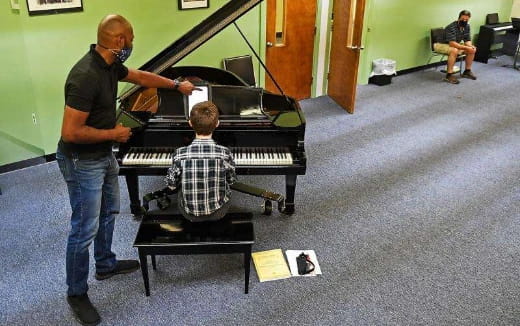 a man playing a piano with a young boy sitting on a chair