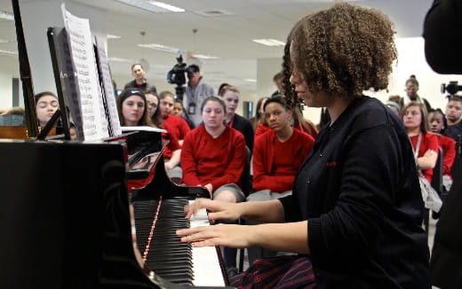 a person playing a piano in front of a group of people