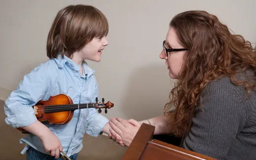 a person playing a violin with a young boy