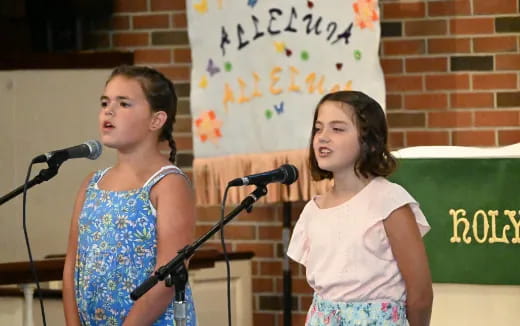 a couple of girls standing in front of microphones