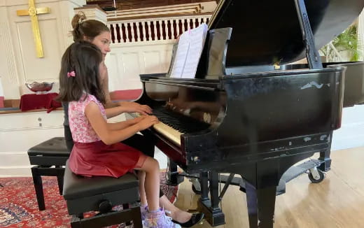 a woman and a girl playing a piano